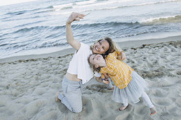 Happy mother taking selfie with daughter at beach - SIF00242