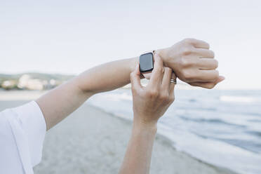 Hand of woman using smart watch at beach - SIF00244