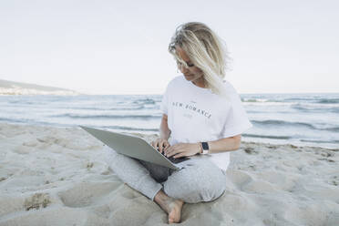 Glückliche Frau mit Laptop am Strand - SIF00248