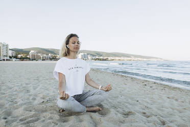 Smiling woman with eyes closed meditating at beach - SIF00253