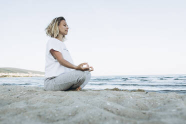 Frau mit geschlossenen Augen beim Yoga am Strand - SIF00254