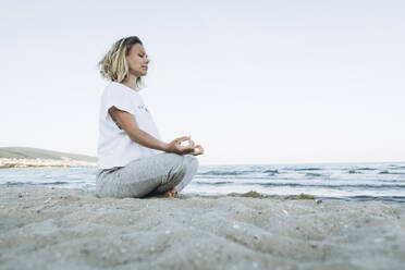 Woman with eyes closed doing yoga at beach - SIF00254