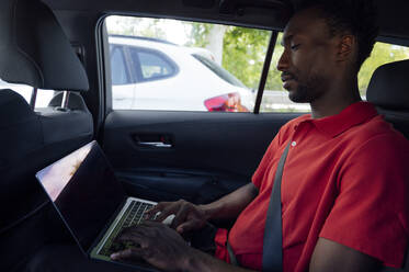 Mann am Laptop im Auto sitzend - PGF01129