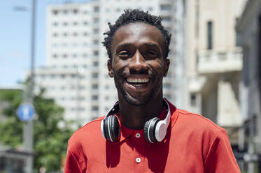 Happy man with wireless headphones on sunny day - PGF01132