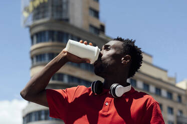 Man drinking coffee from disposable cup on sunny day - PGF01138