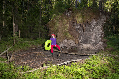 Woman with inflatable ring standing in forest - VPIF06623