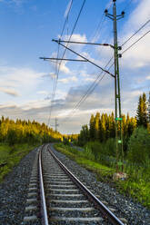 Schweden, Bezirk Jamtland, Are, Leere Bahngleise in der Morgendämmerung mit Waldlandschaft im Hintergrund - STSF03282