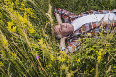 Smiling senior farmer lying amidst plants - UUF26688