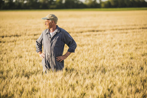 Landwirt steht mit ausgebreiteten Armen auf einem Weizenfeld - UUF26719