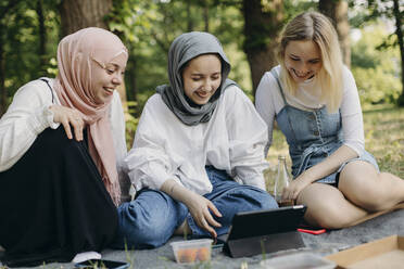 Glückliche Freunde teilen sich einen Tablet-PC im Park - KASF00001