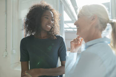 Smiling senior businesswoman talking with colleague in office - KNSF09390