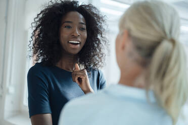 Happy businesswoman talking with colleague in office - KNSF09397