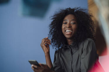 Happy young woman holding smart phone - KNSF09451