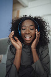 Glückliche junge Frau, die Musik über drahtlose Kopfhörer genießt - KNSF09461