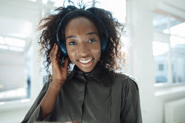 Smiling young woman listening music through wireless headphones - KNSF09471