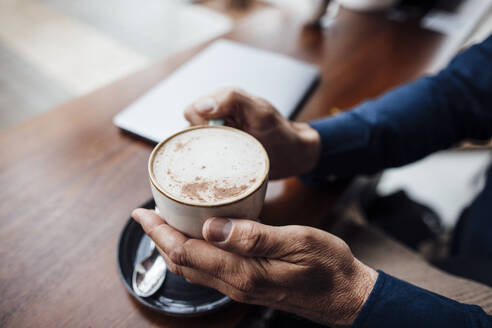 Hände eines Mannes, der eine Kaffeetasse in einem Café hält - JOSEF10825