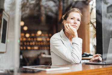 Thoughtful businesswoman with head in hands at cafe - JOSEF10917