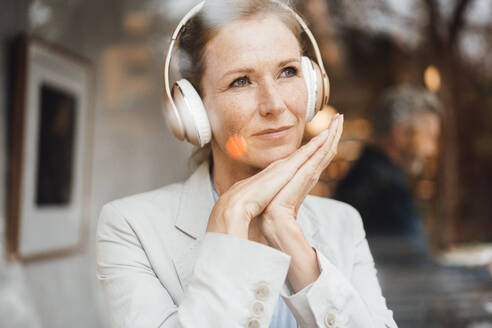 Geschäftsfrau hört Musik über drahtlose Kopfhörer in einem Café - JOSEF10931