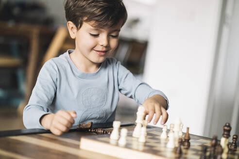 Lächelnder Junge spielt zu Hause Schach - IFRF01705