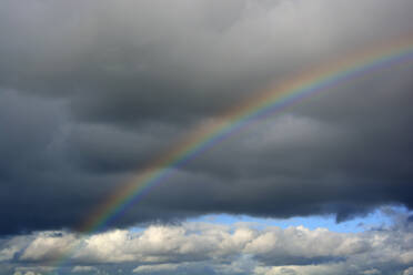 Rainbow arching against gray storm clouds - AXF00863