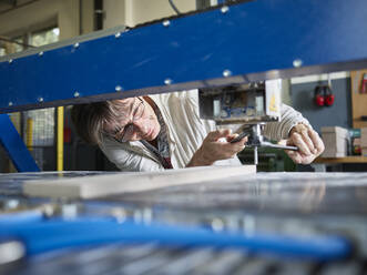 Mature man changing the drill of machine at factory - CVF02035