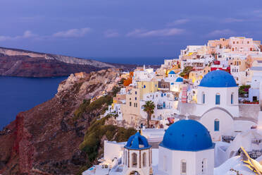 Weiße Kirche mit blauer Kuppel und bunte Gebäude bei Sonnenaufgang, Oia, Santorin, Kykladen, Griechische Inseln, Griechenland, Europa - RHPLF22239