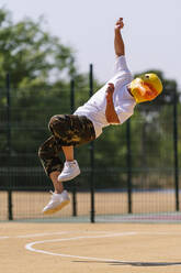 Mann mit Tiermaske springt an einem sonnigen Tag auf dem Sportplatz - OCMF02517