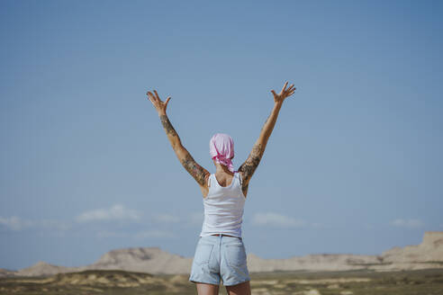 Woman with arms raised standing in Bardenas desert, Spain - MTBF01245