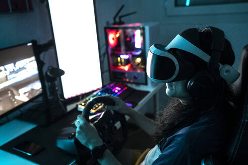 Gamer wearing VR glasses using steering wheel at home - DAMF01000