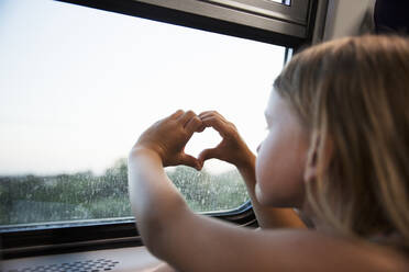 Mädchen macht Herzgeste am Zugfenster - FOLF11524