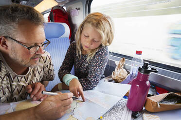 Vater und Tochter betrachten eine Karte im Zug - FOLF11537