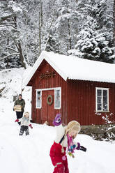 Familie beim Spaziergang im Schnee bei der Hütte - FOLF11538