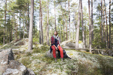 Frau sitzt auf einem Felsen im Wald - FOLF11571