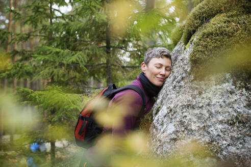 Frau lehnt an einem Felsen im Wald - FOLF11574