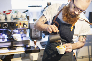 Barista gießt Milch in den Kaffee - FOLF11595