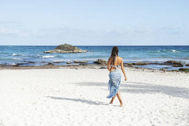 Junge Frau in Bikini und Sarong geht am Strand spazieren - FOLF11603
