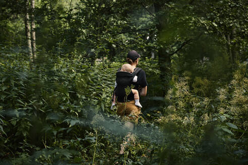 Frau geht mit Tochter im Kinderwagen durch den Wald - FOLF11609
