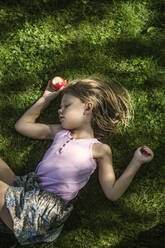 Girl with apple sleeping in grass - FOLF11619