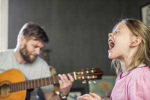 Mädchen singt, während ihr Vater Gitarre spielt - FOLF11620