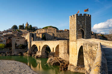 Besalu historische mittelalterliche Stadt mit katalanischen Fahnen auf dem steinernen Brückenturm über den Fluss El Fluvia, Besalu, Katalonien, Spanien, Europa - RHPLF22328