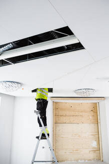 Construction worker on ladder working in ceiling - FOLF11705