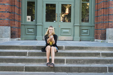 Junge Frau mit Smartphone auf einer Treppe sitzend - FOLF11716