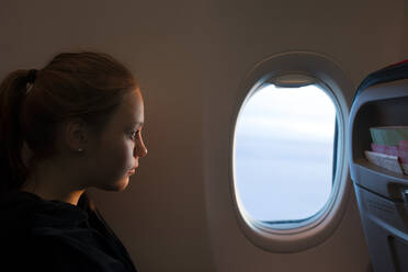 Teenager-Mädchen schaut aus dem Fenster eines Flugzeugs - FOLF11722