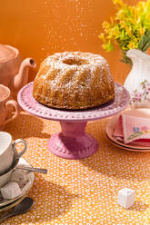 Powdered sugar pouring on freshly made bundt cake - FLMF00821