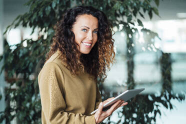 Lächelnde Geschäftsfrau mit Tablet-PC an der Pflanze - JOSEF10965