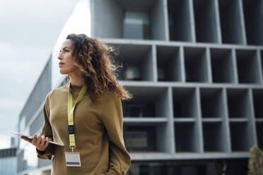 Contemplative businesswoman with tablet PC in front of office building - JOSEF10986