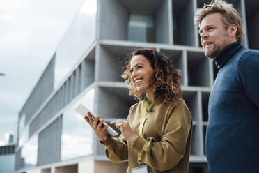 Smiling business colleagues standing by front office building - JOSEF10990