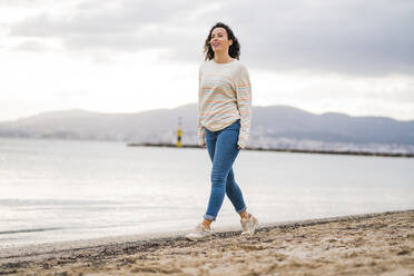 Smiling mature woman walking on beach - JOSEF11009