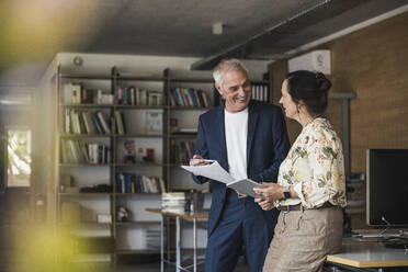 Glückliche Geschäftskollegen bei einer Diskussion im Büro - UUF26756