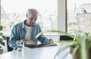 Businessman using tablet PC sitting at desk in office - UUF26822